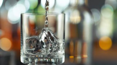 Super Slow Motion Detail Shot of Pouring Transparent Alcohol Liquid into Glass with Ice on Bar at 1000fps. Filmed with High Speed Cinema Camera, 4K.