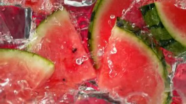 Karpuz dilimleri ve buz küpleri üzerinde su dalgası sıçrayan süper yavaş çekim. 4K 'da Yüksek Hız Sinema Kamerası ile çekildi..