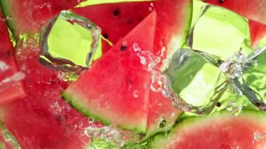 Karpuz dilimleri ve buz küpleri üzerinde su dalgası sıçrayan süper yavaş çekim. 4K 'da Yüksek Hız Sinema Kamerası ile çekildi..