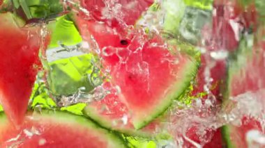 Karpuz dilimleri ve buz küpleri üzerinde su dalgası sıçrayan süper yavaş çekim. 4K 'da Yüksek Hız Sinema Kamerası ile çekildi..