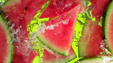 Karpuz dilimleri ve buz küpleri üzerinde su dalgası sıçrayan süper yavaş çekim. 4K 'da Yüksek Hız Sinema Kamerası ile çekildi..