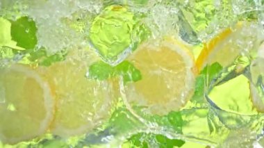 Limon dilimleri, buz küpleri ve yapraklar üzerinde su sıçrayan süper yavaş çekim sahnesi. 4K 'da Yüksek Hız Sinema Kamerası ile çekildi..