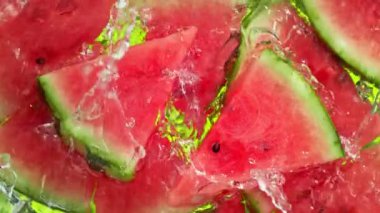 Karpuz dilimleri ve buz küpleri üzerinde su dalgası sıçrayan süper yavaş çekim. 4K 'da Yüksek Hız Sinema Kamerası ile çekildi..