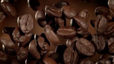 Kahverengi Soyut Arkaplan 'da Flying Premium Coffee Beans' in Süper Yavaş Film Macro Shot 'u. Yüksek Hız Sinema Kamerası, 4k.