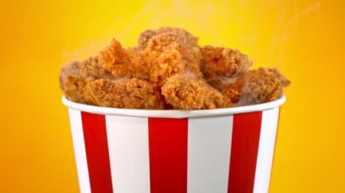 Slow Motion shot of Fried Chicken Pieces ve Smoke Rotting in a Bucket on Golden Background. Yüksek Hız Sinema Kamerası, 4K.