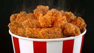 Slow Motion Shot of Fried Chicken Pieces ve Smoke Rotting in a Bucket on Black Fground. Yüksek Hız Sinema Kamerası, 4K.
