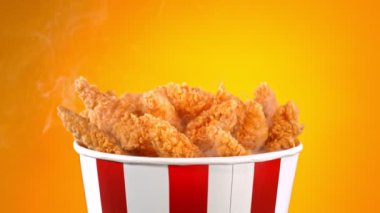 Slow Motion shot of Fried Chicken Pieces ve Smoke Rotting in a Bucket on Golden Background. Yüksek Hız Sinema Kamerası, 4K.