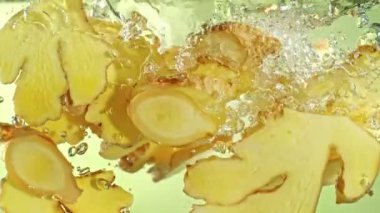 Ginger Dilimlerinin suya düşüşünün Süper Yavaş Çekimi. Yüksek Hız Sinema Kamerası, 4K.