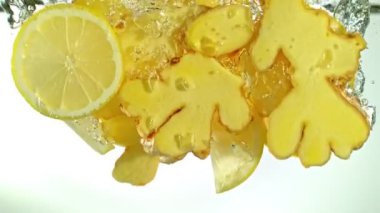 Ginger Dilimlerinin Süper Yavaş Çekimi ve Beyaz Suya Düşerken Limon Dilimleri. Yüksek Hız Sinema Kamerası, 4K.