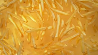 Altın Arkaplan 'daki kameraya doğru uçan patates kızartmasının süper yavaş çekim sahnesi. Yüksek Hız Sinema Kamerası, 4K.