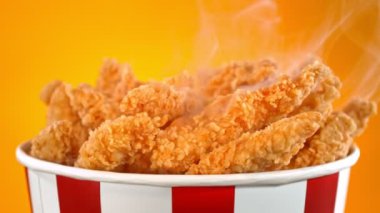 Slow Motion shot of Fried Chicken Pieces ve Smoke Rotting in a Bucket on Golden Background. Yüksek Hız Sinema Kamerası, 4K.