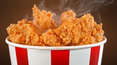 Slow Motion Shot of Fried Chicken Bites and Smoke Rotating in a Bucket.