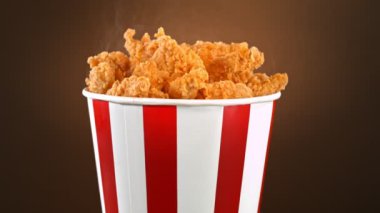 Slow Motion Shot of Fried Chicken Bites and Smoke Rotating in a Bucket.