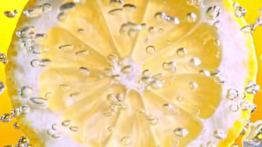 Köpüklü suda bir dilim limon, canlı ve ferahlatıcı bir görüntü yaratır, temiz ve lezzetli bir his verir..
