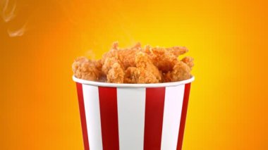 Slow Motion shot of Fried Chicken Pieces ve Smoke Rotting in a Bucket on Golden Background. Yüksek Hız Sinema Kamerası, 4K.