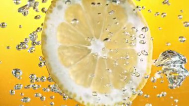 Köpüklü suda bir dilim limon, canlı ve ferahlatıcı bir görüntü yaratır, temiz ve lezzetli bir his verir..