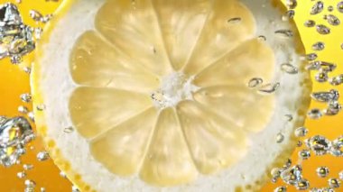 Köpüklü suda bir dilim limon, canlı ve ferahlatıcı bir görüntü yaratır, temiz ve lezzetli bir his verir..