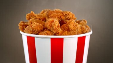 Slow Motion shot of Fried Chicken Pieces ve Smoke Rotting in a Bucket on Golden Background. Yüksek Hız Sinema Kamerası, 4K.