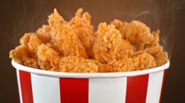 Slow Motion shot of Fried Chicken Pieces ve Smoke Rotting in a Bucket on Brown Background. Yüksek Hız Sinema Kamerası, 4K.