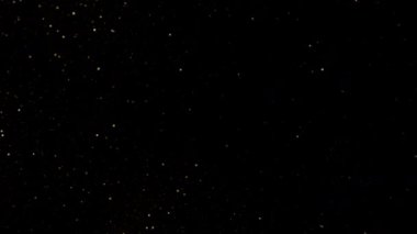 Kara Arkaplan 'da yavaşça yanıp sönen altın parıltıların süper yavaş çekim çekimi. Yüksek Hız Sinema Kamerası, 4K.