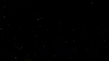 Kara Arkaplan 'da yavaşça yanıp sönen altın parıltıların süper yavaş çekim çekimi. Yüksek Hız Sinema Kamerası, 4K.