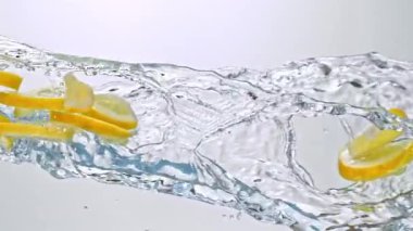 Limon Dilimlerinin Süper Yavaş Hareketi Beyaz Arkaplanda Su Sıçratarak Uçuyor. Yüksek Hız Sinema Kamerası, 4K.