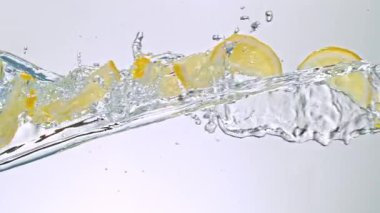 Limon Dilimlerinin Süper Yavaş Hareketi Beyaz Arkaplanda Su Sıçratarak Uçuyor. Yüksek Hız Sinema Kamerası, 4K.
