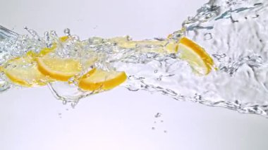 Limon Dilimlerinin Süper Yavaş Hareketi Beyaz Arkaplanda Su Sıçratarak Uçuyor. Yüksek Hız Sinema Kamerası, 4K.
