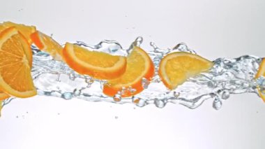 Portakal Dilimlerinin Süper Yavaş Hareketi Beyaz Arkaplanda Su Sıçratarak Uçuyor. Yüksek Hız Sinema Kamerası, 4K.