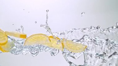 Limon Dilimlerinin Süper Yavaş Hareketi Beyaz Arkaplanda Su Sıçratarak Uçuyor. Yüksek Hız Sinema Kamerası, 4K.
