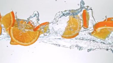 Portakal Dilimlerinin Süper Yavaş Hareketi Beyaz Arkaplanda Su Sıçratarak Uçuyor. Yüksek Hız Sinema Kamerası, 4K.