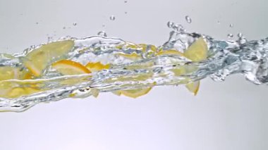 Limon Dilimlerinin Süper Yavaş Hareketi Beyaz Arkaplanda Su Sıçratarak Uçuyor. Yüksek Hız Sinema Kamerası, 4K.