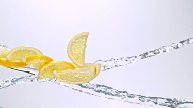 Limon Dilimlerinin Süper Yavaş Hareketi Beyaz Arkaplanda Su Sıçratarak Uçuyor. Yüksek Hız Sinema Kamerası, 4K.