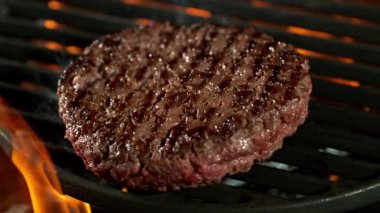Alevler ve közlerle kızgın ızgarada pişmiş hamburgerin süper yavaş çekim çekimi. Yüksek Hız Sinema Kamerası, 4K.