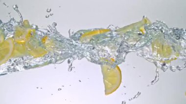 Limon Dilimlerinin Süper Yavaş Hareketi Beyaz Arkaplanda Su Sıçratarak Uçuyor. Yüksek Hız Sinema Kamerası, 4K.