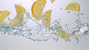 Limon Dilimlerinin Süper Yavaş Hareketi Beyaz Arkaplanda Su Sıçratarak Uçuyor. Yüksek Hız Sinema Kamerası, 4K.