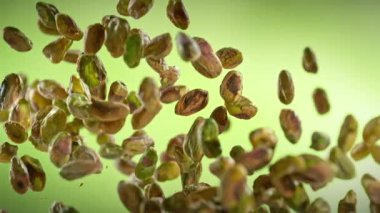 Taze Soyulmuş Pistachio Fındıklarının Süper Yavaş Çekimi. Yeşil Arka planda Uçuyor. Yüksek Hız Sinema Kamerası, 4K.