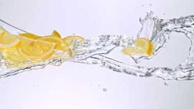 Limon Dilimlerinin Süper Yavaş Hareketi Beyaz Arkaplanda Su Sıçratarak Uçuyor. Yüksek Hız Sinema Kamerası, 4K.