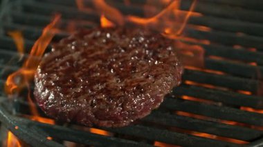 Alevler ve közlerle kızgın ızgarada pişmiş hamburgerin süper yavaş çekim çekimi. Yüksek Hız Sinema Kamerası, 4K.