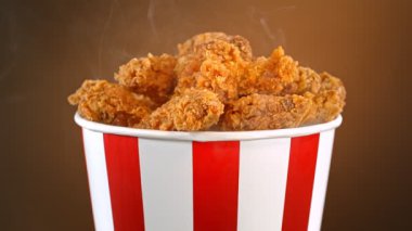 Slow Motion shot of Fried Chicken Pieces ve Smoke Rotting in a Bucket on Brown Background. Yüksek Hız Sinema Kamerası, 4K.