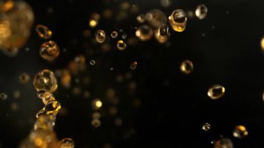 Kara Arkaplanda Uçan Altın Sıvı Damlalarının Süper Yavaş Çekimi. Yüksek Hız Sinema Kamerası, 4K.