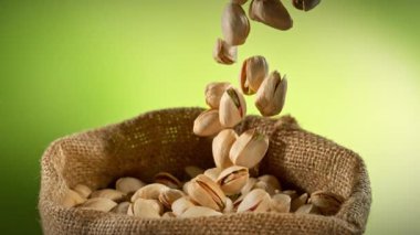 Pistachio Nuts 'ın Süper Yavaş Çekimi, Gradyan Arkaplan' da Jute Bag 'in içine düşüyor. Yüksek Hız Sinema Kamerası, 4K.