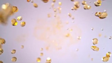 Uçan Altın Sıvı Düşürmenin Süper Yavaş Çekimi Işık Arkaplan 'daki Kameraya doğru 1000fps' de. Yüksek Hız Sinema Kamerası, 4K.