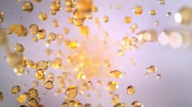 Uçan Altın Sıvı Düşürmenin Süper Yavaş Çekimi Işık Arkaplan 'daki Kameraya doğru 1000fps' de. Yüksek Hız Sinema Kamerası, 4K.
