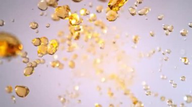 Hafif Arkaplanda Uçan Altın Sıvı Düşüşü 'nün Süper Yavaş Çekimi. Yüksek Hız Sinema Kamerası, 4K.