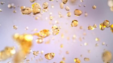 Hafif Arkaplanda Uçan Altın Sıvı Düşüşü 'nün Süper Yavaş Çekimi. Yüksek Hız Sinema Kamerası, 4K.