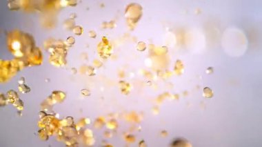 Hafif Arkaplanda Uçan Altın Sıvı Düşüşü 'nün Süper Yavaş Çekimi. Yüksek Hız Sinema Kamerası, 4K.