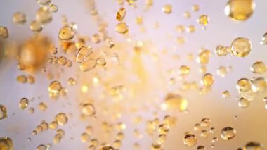 Hafif Arkaplanda Uçan Altın Sıvı Düşüşü 'nün Süper Yavaş Çekimi. Yüksek Hız Sinema Kamerası, 4K.
