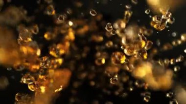 Kara Arkaplanda Uçan Altın Sıvı Damlalarının Süper Yavaş Çekimi. Yüksek Hız Sinema Kamerası, 4K.