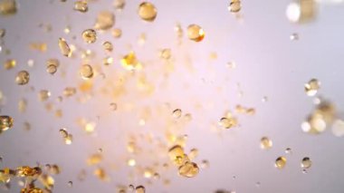Hafif Arkaplanda Uçan Altın Sıvı Düşüşü 'nün Süper Yavaş Çekimi. Yüksek Hız Sinema Kamerası, 4K.